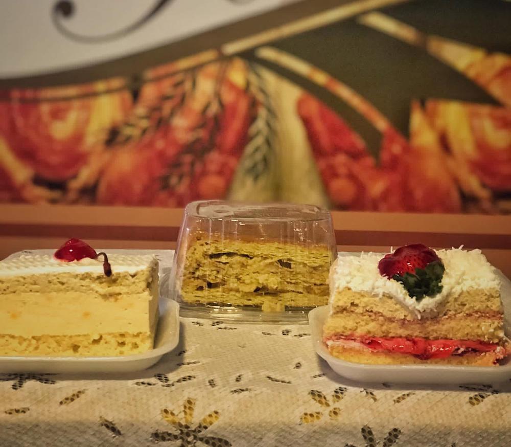 Porciones de milhoja, torta de fresa con coco y torta de vainilla frente al letrero de La Torre